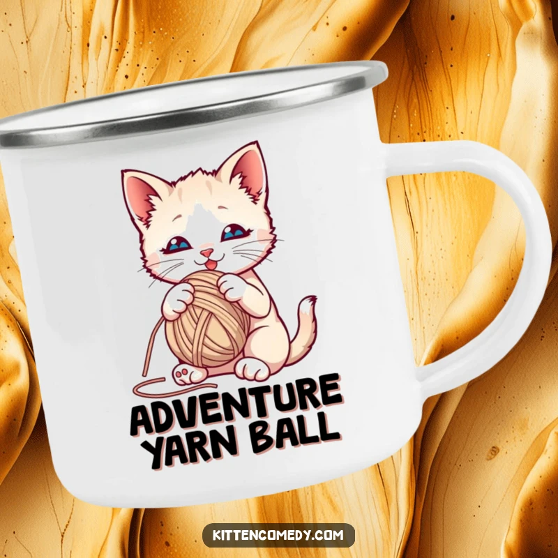 Funny kitten playfully batting at a yarn ball on an enamel camping mug, perfect for outdoor fun.