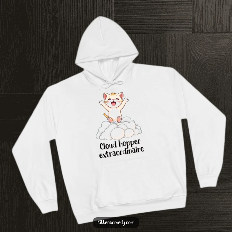 Funny hoodie featuring a delighted kitten character soaring through the sky, joyfully leaping into a luxurious pile of soft clouds.