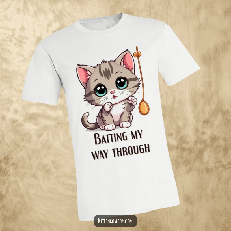 Funny kitten batting at a dangling string with wide, curious eyes, a playful t-shirt for a funny gift.