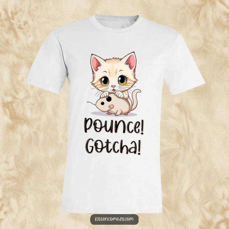 Funny kitten with wide, determined eyes pouncing on a toy mouse on a t-shirt, capturing a moment of playful hunting.