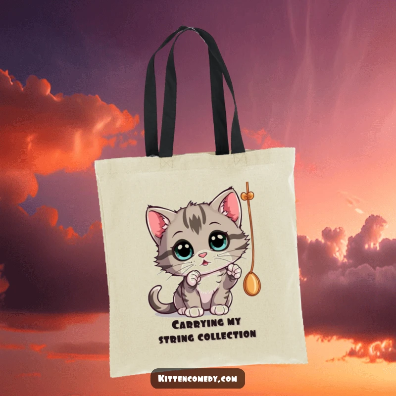 Funny kitten batting at a dangling string with wide eyes, a stylish tote bag for a funny gift.